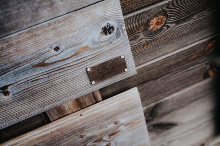 A weathered Thermory cladding sample with a dated brass plaque